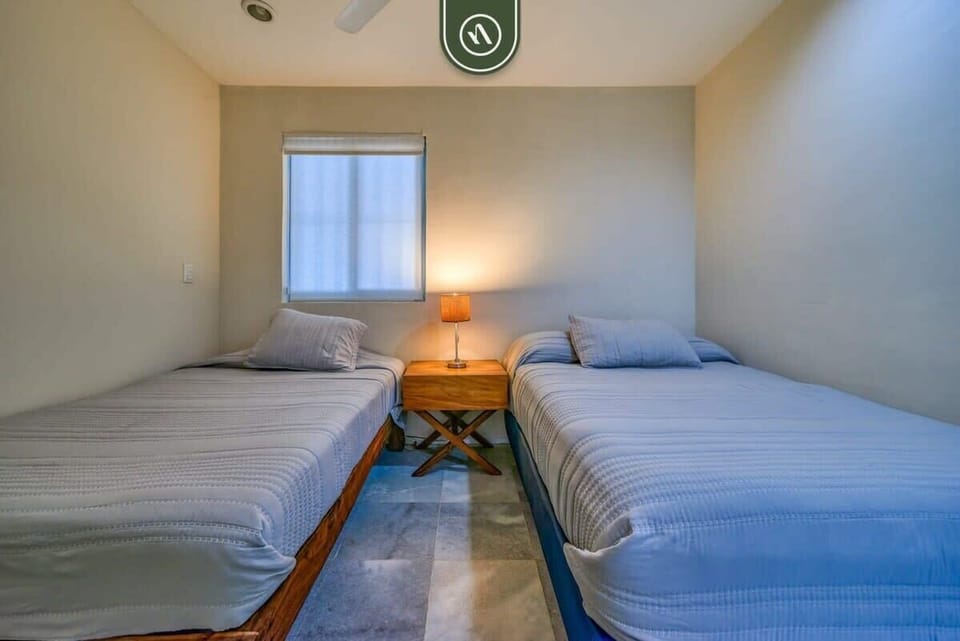 A calm retreat featuring two twin beds and clean, modern decor. Ideal for kids or friends, this peaceful room ensures everyone has a comfortable space to relax after a day at the beach.