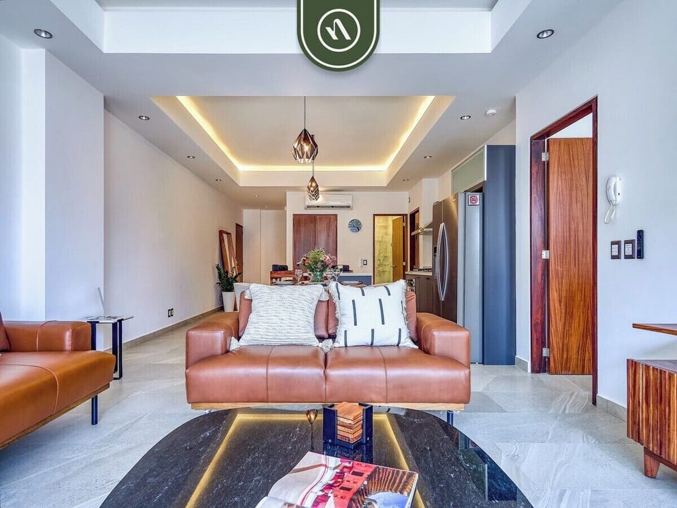 Bright, stylish living space with plush leather sofas, modern lighting, and seamless indoor-outdoor flow for relaxing or entertaining.