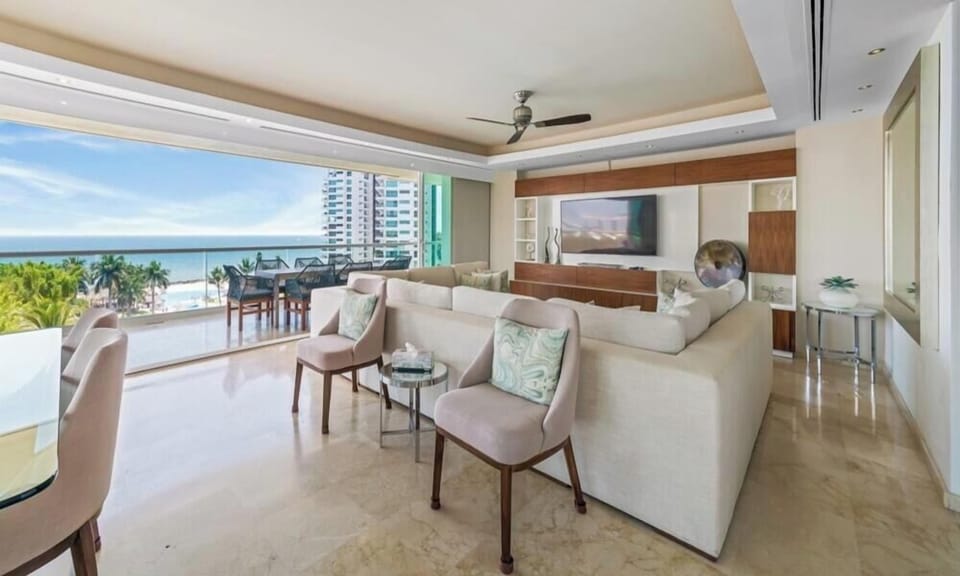 Bright and spacious main living area with a large sectional sofa, contemporary media unit, and fully pocketing glass doors that open to the ocean breeze.