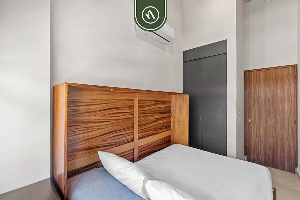 This bright bedroom showcases a warm wood-grain bed frame and sleek charcoal cabinetry, offering a clean and sophisticated retreat for visitors.