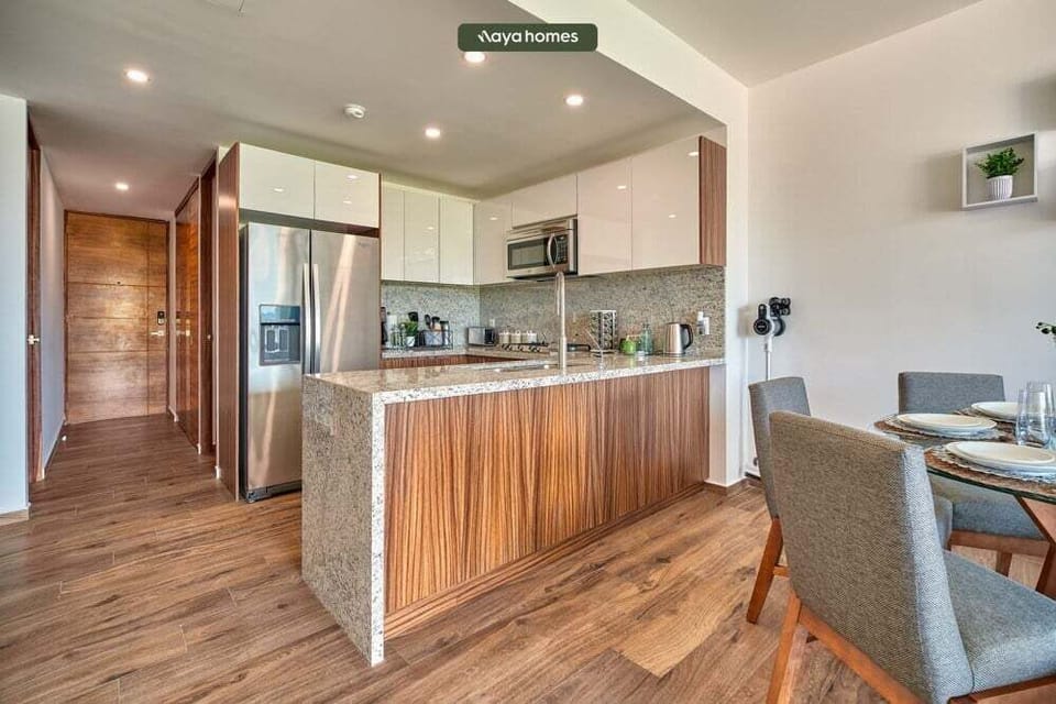 Sleek kitchen space featuring polished granite countertops, warm wood-paneled cabinetry, stainless steel appliances, and wood-look flooring.