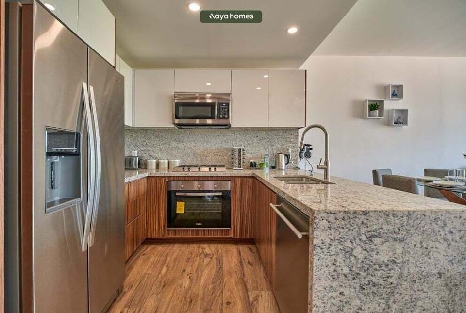 Functional U-shaped kitchen showcasing polished granite countertops, warm wood-grain cabinets, a stainless steel refrigerator, and built-in appliances.