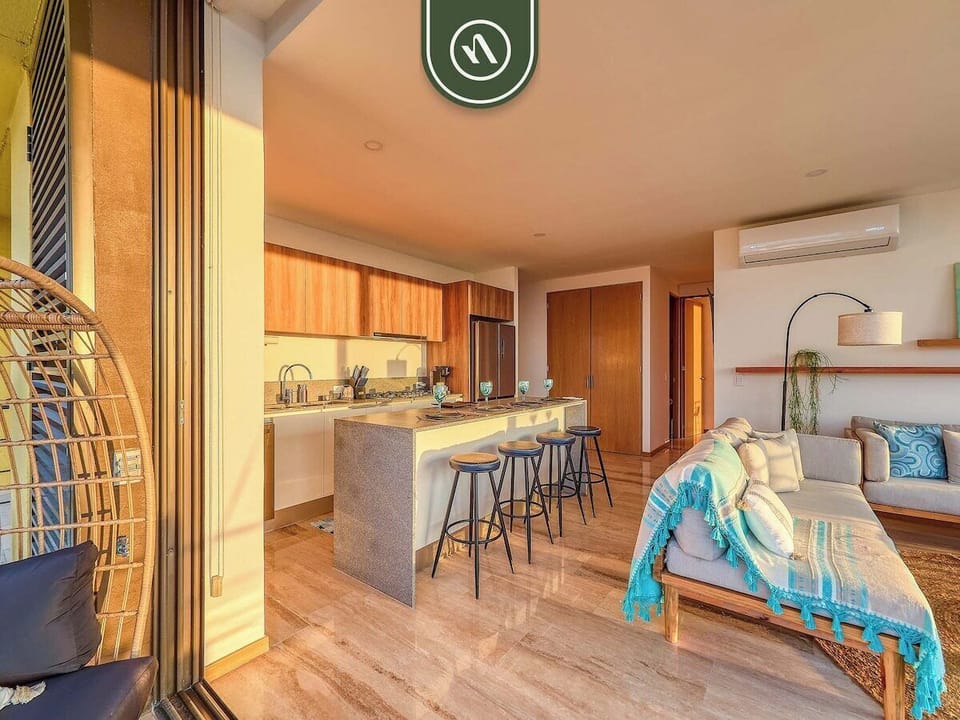 A view across the bright apartment highlighting the smooth transition from the contemporary kitchen breakfast bar into the comfortable living room area.