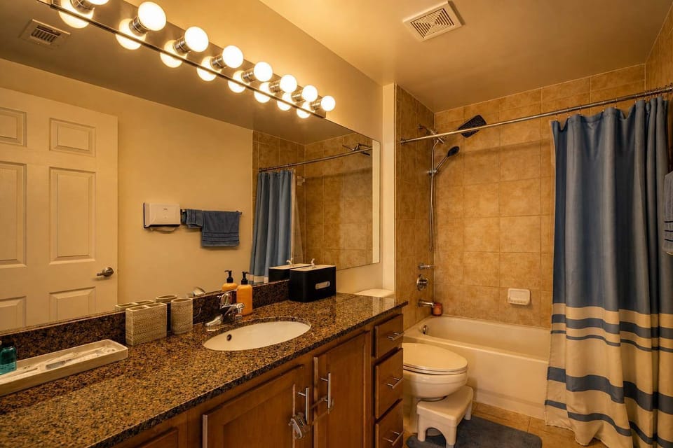 Full bathroom with granite vanity and tub/shower combo — book now for comfort and convenience.