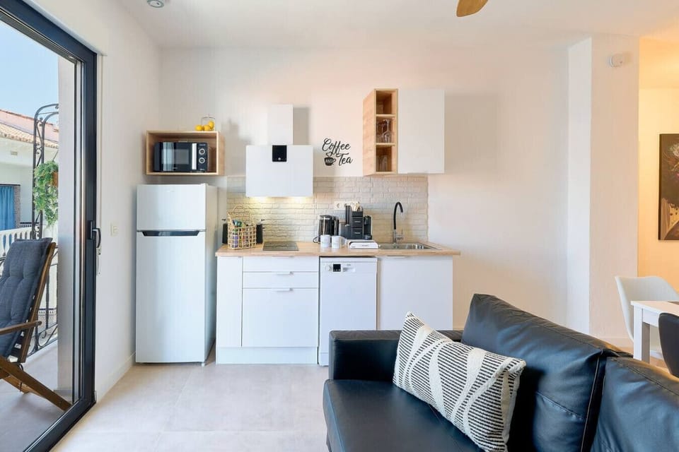 Open-plan kitchen with fridge, two ceramic hubs, dishwasher, washing sink, Nespresso machine, kettle, and microwave.