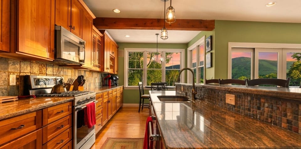 A spacious kitchen featuring stunning granite countertops and a breakfast bar with a view of Mt Snow