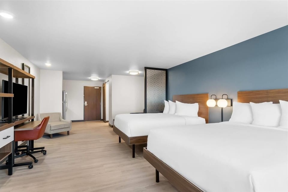Unwind in a roomy double-queen suite with warm bedside glow.