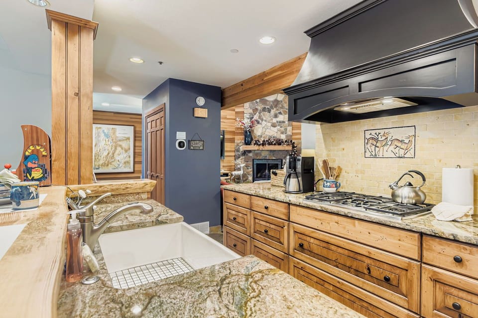 Prepare gourmet meals in this fully equipped kitchen featuring sleek granite countertops, rustic wood cabinetry, and a large farmhouse-style sink.