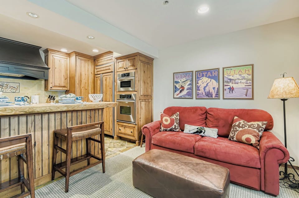 Relax in this cozy space with a plush red sectional and rustic wooden bar area. The compact kitchenette is perfect for light meals in your Park City escape.