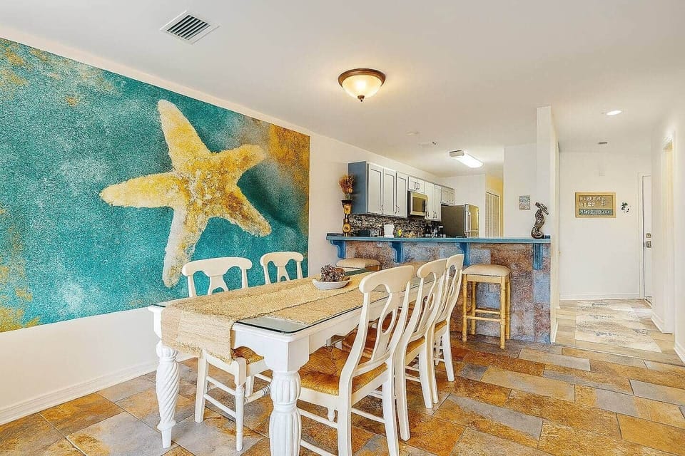 Coastal living & dining with bold starfish mural and seating for 6 in open-concept layout.