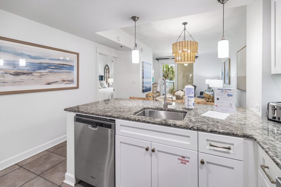 Your open kitchen is beautifully appointed with granite counters and modern appliances, where coastal-inspired décor and soft pendant lights create a warm, inviting space.