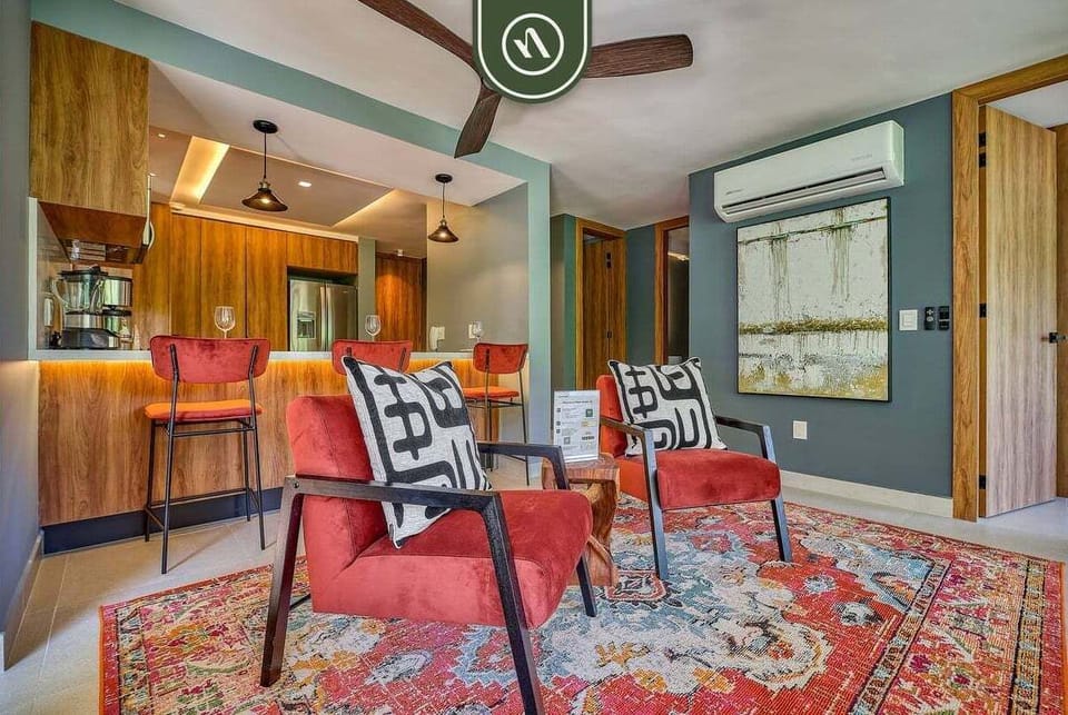 Bright, airy living space with colorful accents, plush seating, and floor-to-ceiling glass doors that open to lush jungle views and the terrace.
