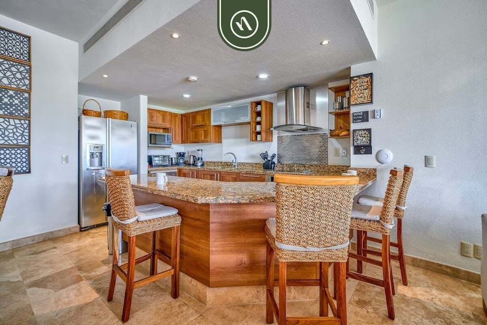 This spacious kitchen features a large granite island with stylish woven barstools. It's the perfect spot for casual dining, morning coffee, or entertaining while you cook.