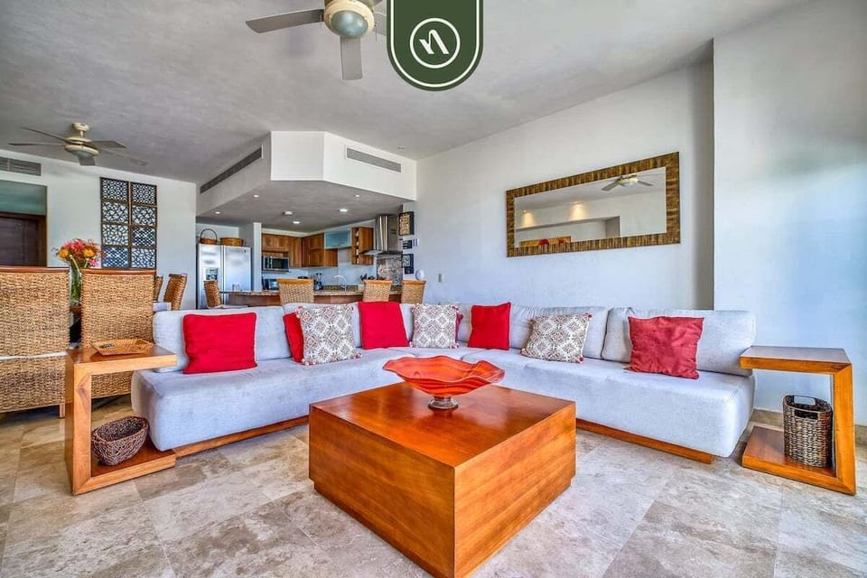 Relax in this expansive open-concept living space. Featuring a large sectional with vibrant accents, a custom wood coffee table, and an airy atmosphere perfect for group gatherings.