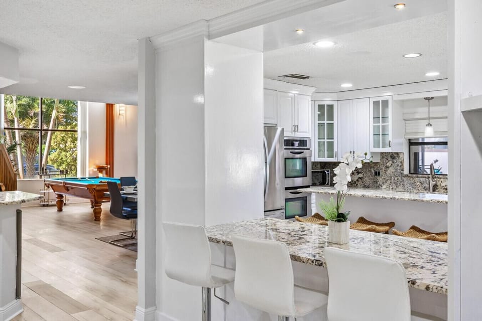 Modern kitchen featuring luxurious granite finishes, large breakfast bar, and family game amenities