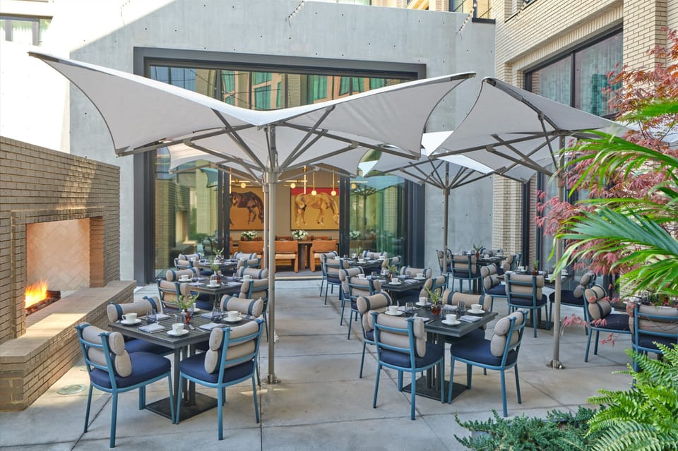 Savor alfresco dining beneath umbrellas beside the warm fire glow.