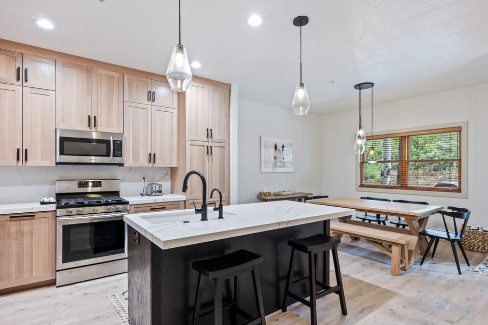 - Modern kitchen with stainless steel appliances and sleek countertops  
- Dining table with benches offers space for family meals and gatherings  
- Pendant lights brighten the open layout with warm inviting ambiance
