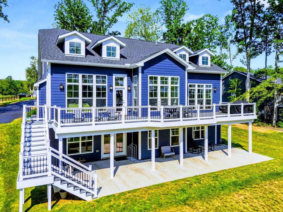 Drone View - The full home from above, with tiered Trex decks, a covered lower porch, and the lake just steps from the back door.