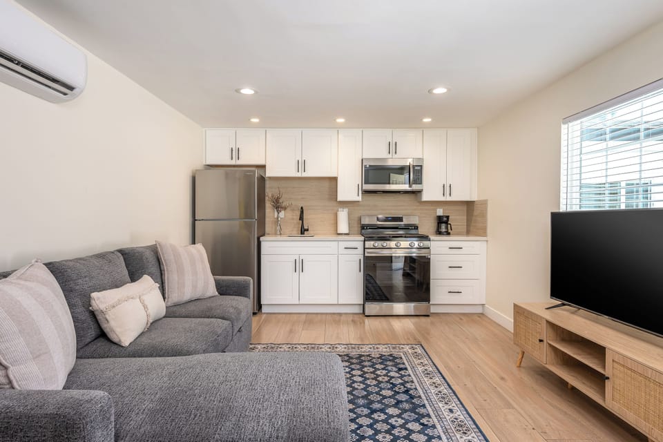 Stylish living room with sectional sofa, smart TV, and full kitchenette.