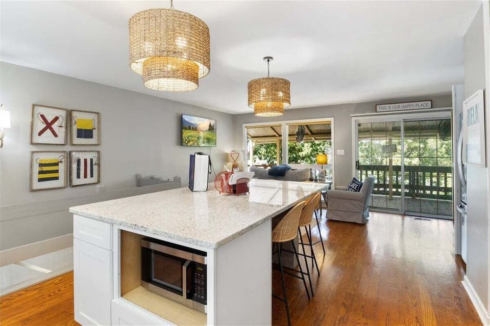 A reverse kitchen view highlights the island, storage, and direct connection to the living room and lake-facing doors.