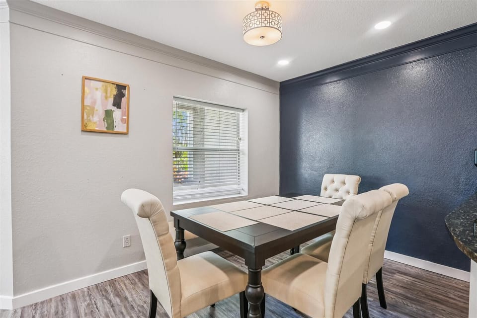 - Dining space with cushioned chairs and bright window views  
- Dark accent wall adds a touch of modern coastal charm  
- Ideal for enjoying meals and conversation together  