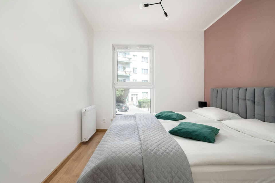 Another angle of the bedroom showing a tall window allowing in plenty of daylight.