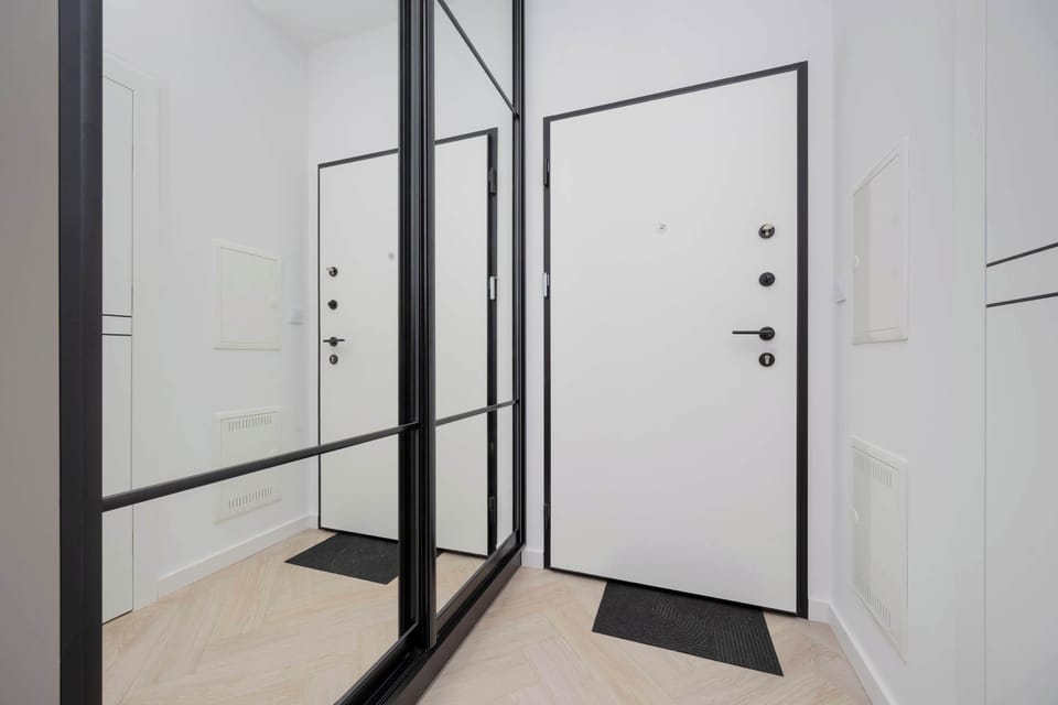 Entry area of the apartment with a modern glass door and clean lines. A mirror and console table add functionality and style.
