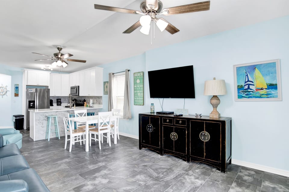 Living room with wall mounted smart TV, 2 ceiling fans, leather sleeper sofa, 2 leather rocker recliners and balcony access with breathtaking view