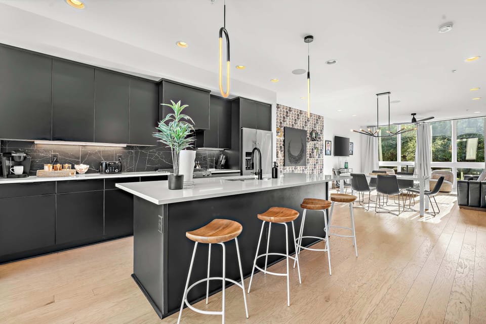 Stunning chef's kitchen showcasing sleek black cabinetry and a massive waterfall island.
