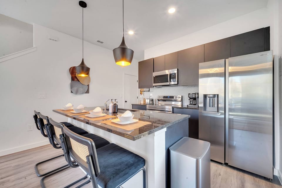 Experience a stylish kitchen featuring dark cabinetry and a stunning stone countertop, perfect for culinary creations. Modern pendant lighting sets a warm atmosphere over the chic bar seating, inviting you to enjoy meals together.