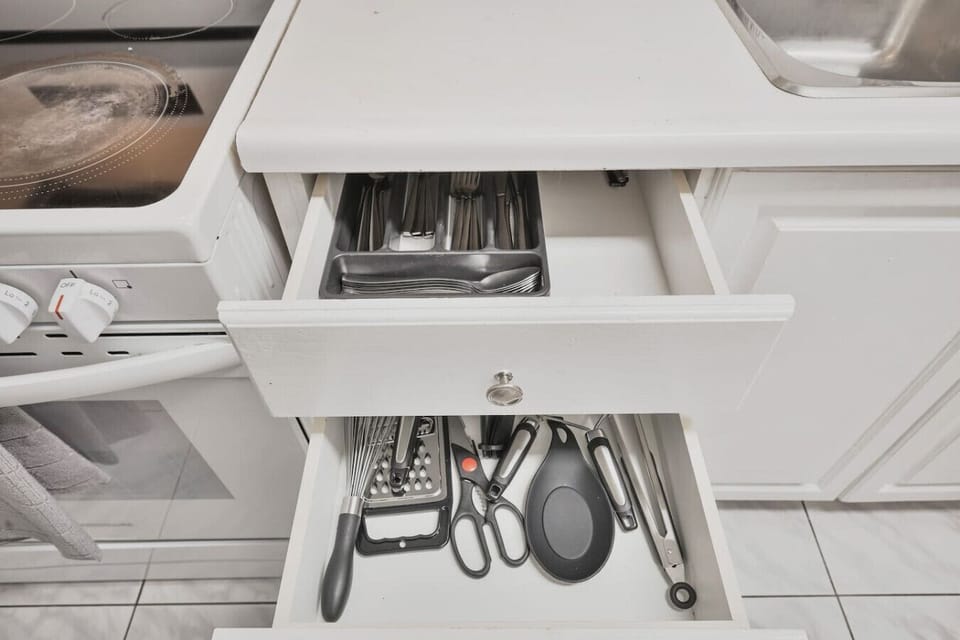 Our fully stocked kitchen includes everything you need. Find clean silverware in the top drawer and essential cooking tools like whisks, scissors, and tongs right below. Effortless dining awaits.