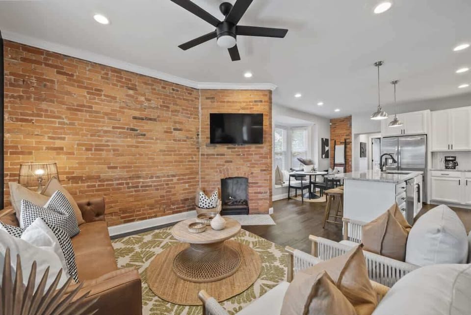 Open living area w/ brick fireplace, TV, & seamless flow into the dining space