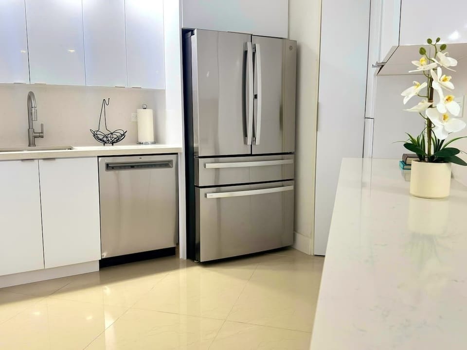Spacious and fully equipped kitchen featuring a large refrigerator, blender, air fryer, microwave, coffee maker, complete dinnerware set, utensils, wine glasses, mugs, pots, and pans—perfect for cooking your favorite meals.
