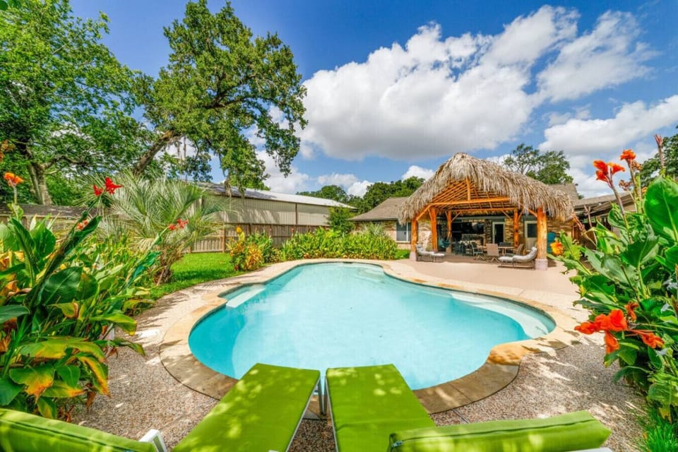 Escape to your private paradise featuring a sparkling pool, lush landscaping, and shaded cabana seating.