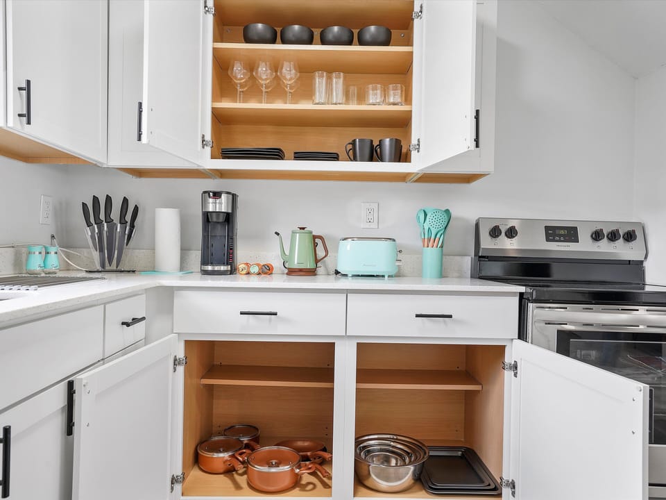 Fully stocked kitchen with cookware, utensils, coffee maker, and toaster.