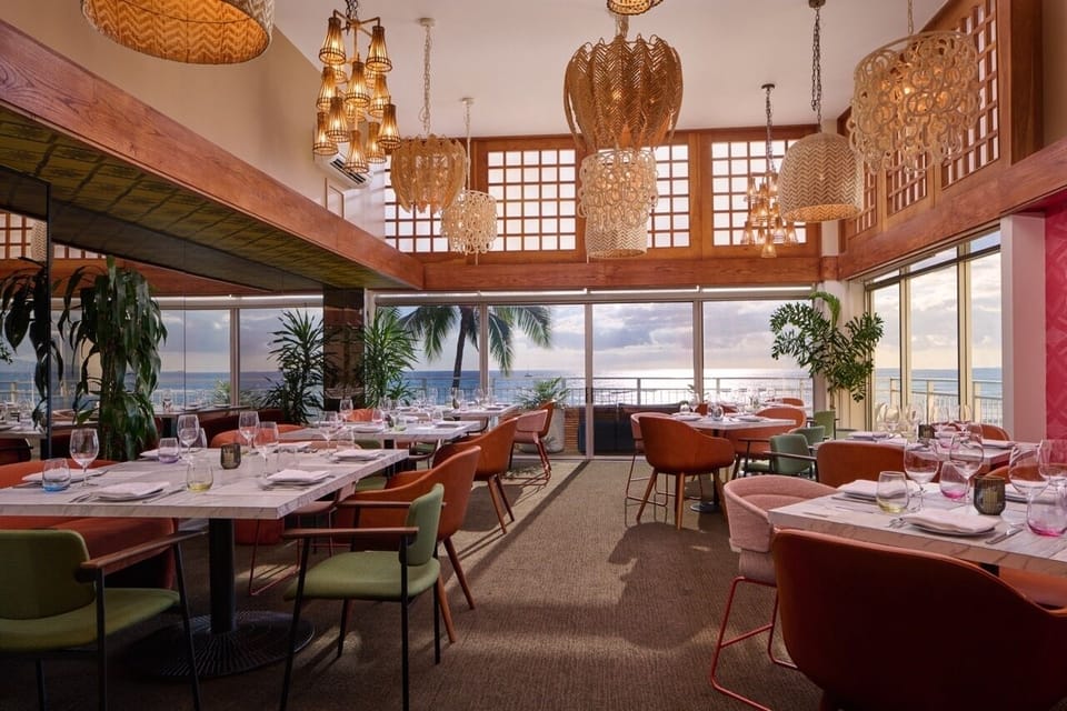 Linger over dinner as palm silhouettes frame the water.