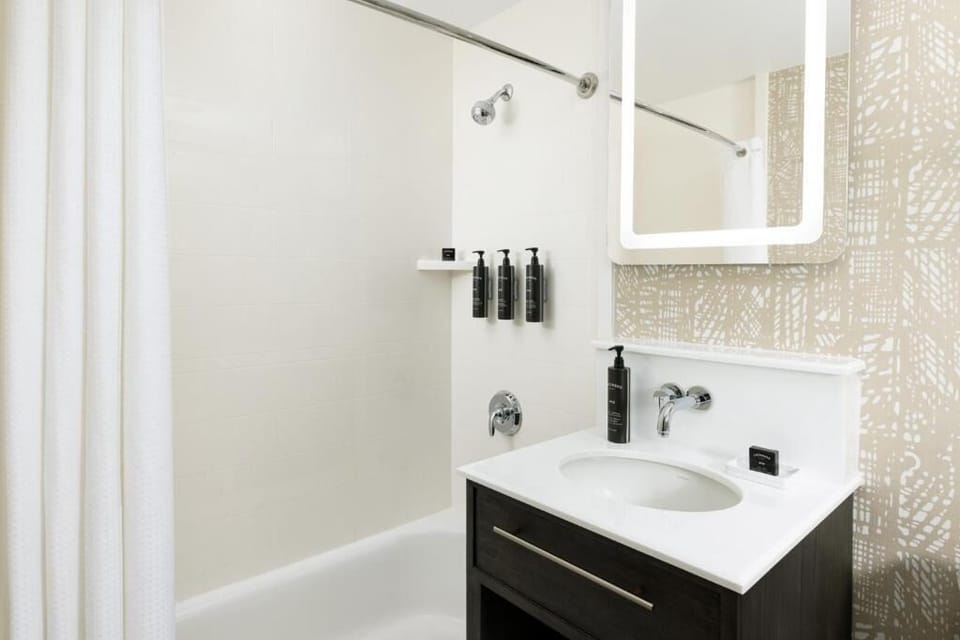Refresh with a spotless tub-shower and bright vanity lighting.