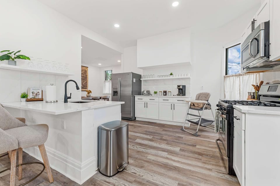 This beautiful kitchen, featuring elegant white cabinets and a chic bar stool, is the ideal backdrop for culinary adventures and heartwarming gatherings.
