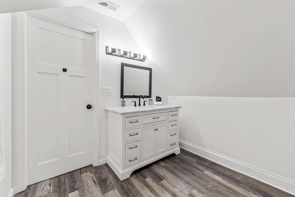 This bathroom's blend of a crisp white door and warm wooden floors creates the perfect retreat. 