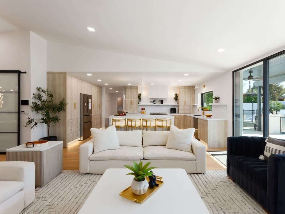 Bright open floor living space, designer furnishings, smart TV, and large sliding doors leading to the private resort-style backyard.