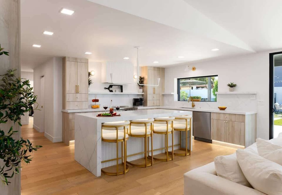 Fully equipped kitchen with stainless steel appliances, a sleek kitchen island with a breakfast bar for casual seating for 4.