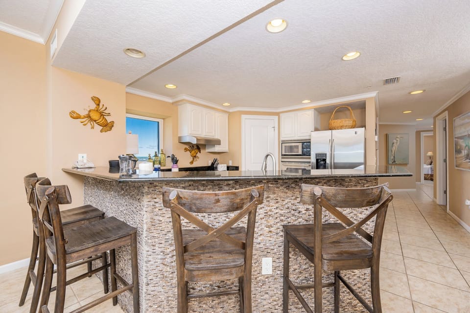 This modern kitchen features sleek granite countertops, stainless appliances, and a cozy breakfast bar with an area view