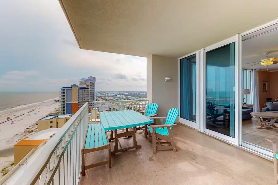 This balcony features vibrant turquoise seating and a stunning beachfront view, perfect for relaxing or dining outdoors