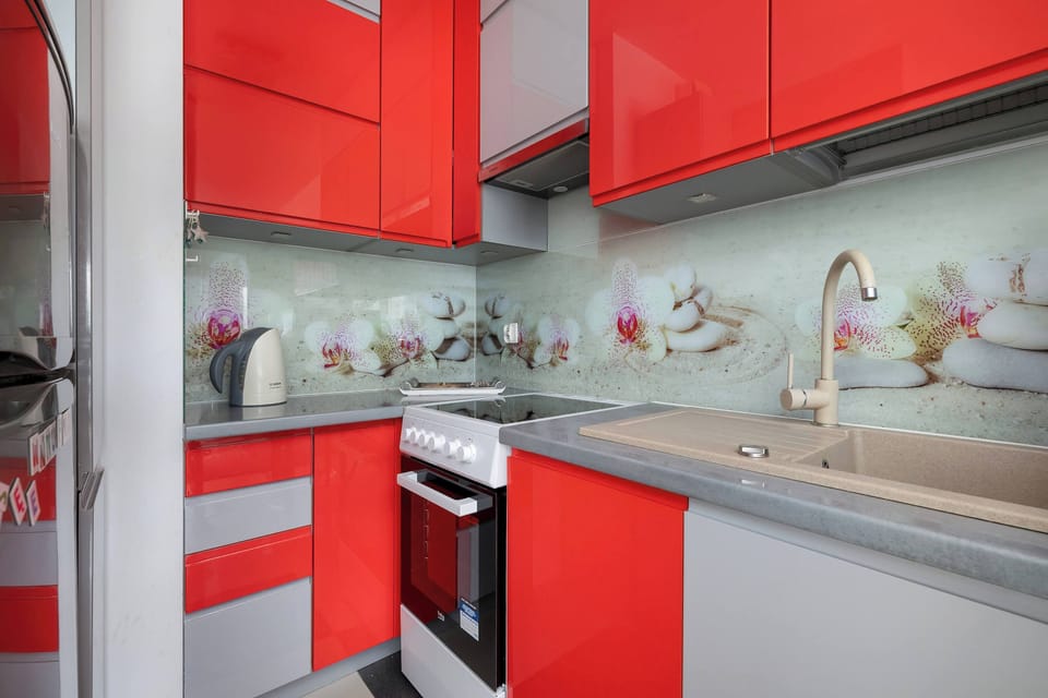 Kitchen with red accents – Bright and functional with artistic backsplash.