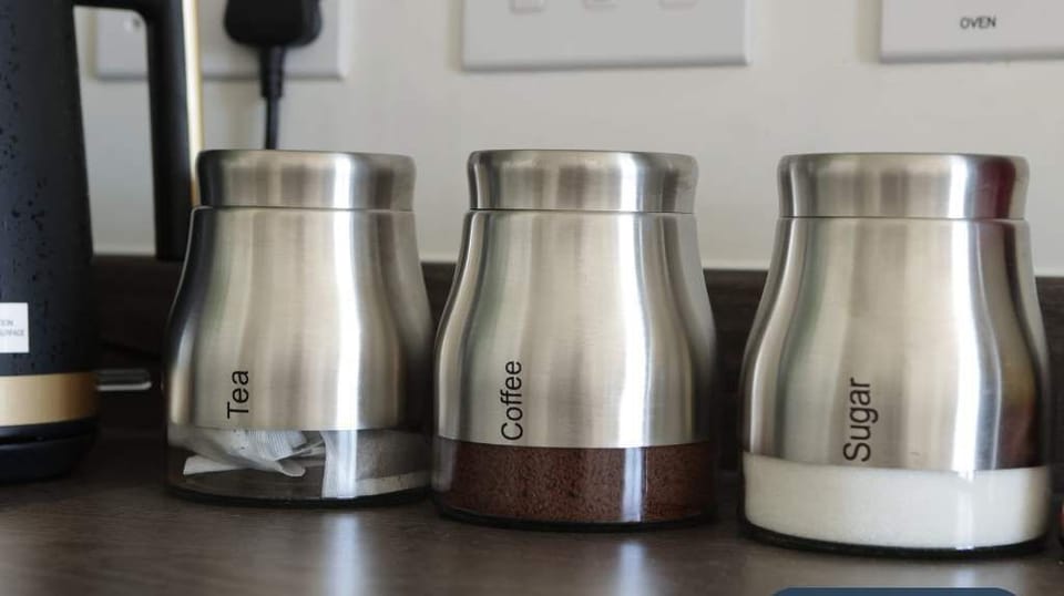 Set of sleek stainless steel canisters for tea, coffee, and sugar, neatly arranged on the kitchen counter. Adds a touch of modern organisation and convenience for guests who enjoy preparing hot drinks during their stay.