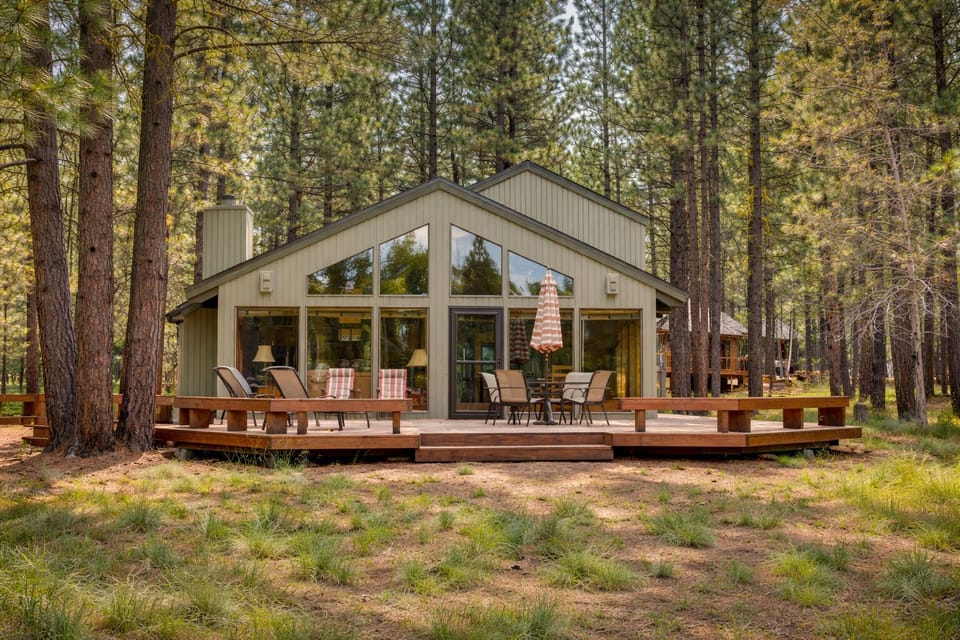 Modern forest retreat with expansive windows and spacious deck, surrounded by towering pine trees for the perfect woodland getaway.