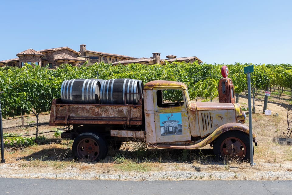 A vintage farm truck loaded with wine barrels adds a rustic touch among the vineyard rows.