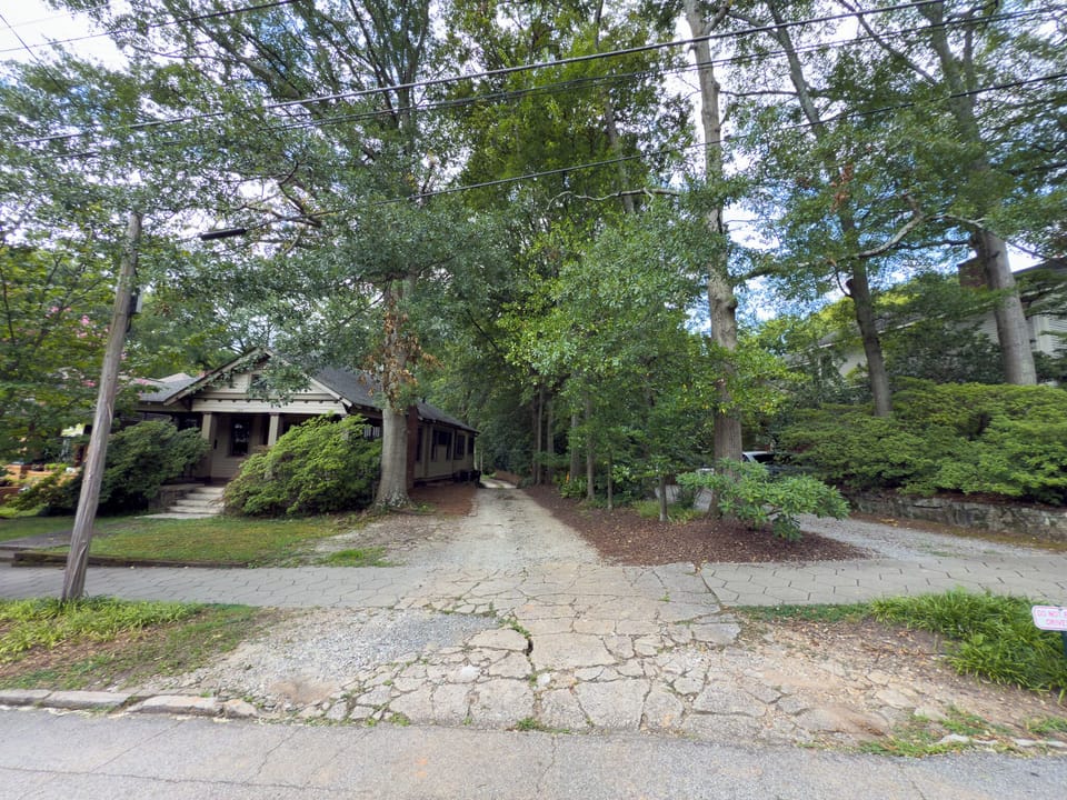 Quiet street approach w/ tree canopy leading toward the home