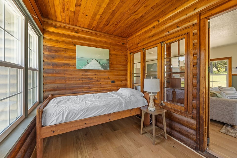 Cozy wood-paneled nook with a single bed and bright natural light.