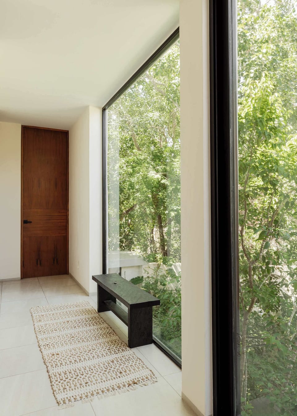 Bedroom with built-in wooden wardrobe and large window framing lush tropical garden.
